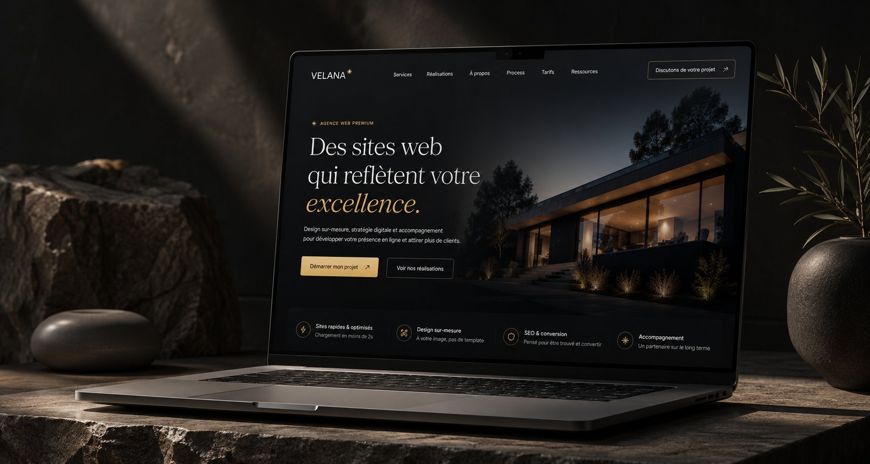 Le site Velana affiché sur un ordinateur portable, dans une mise en scène sobre en pierre et lumière chaude